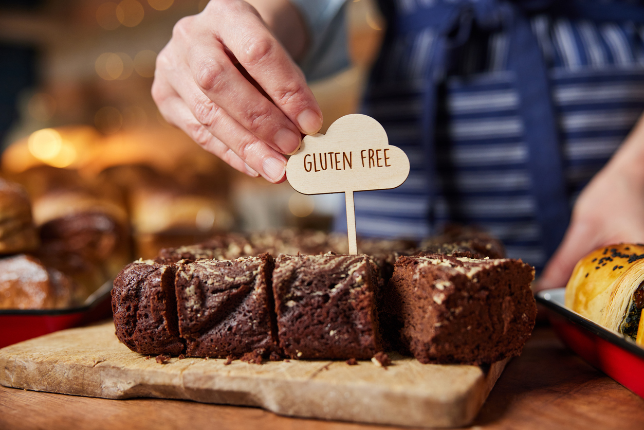 Sales assistant in bakery putting gluten free label into freshly baked brownies
