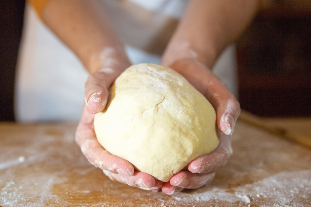 Unrecognizable baker holding kneaded dough in palms