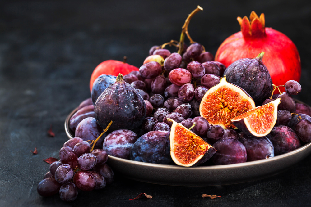 Fresh autumn fruits - figs, plums, grapes and pomegranate on dark background